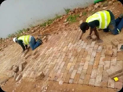 Workers in high visibility clothing laying brick paving by hand