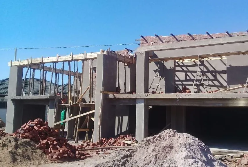 Double storey concrete frame structure under construction with brick stacks on site
